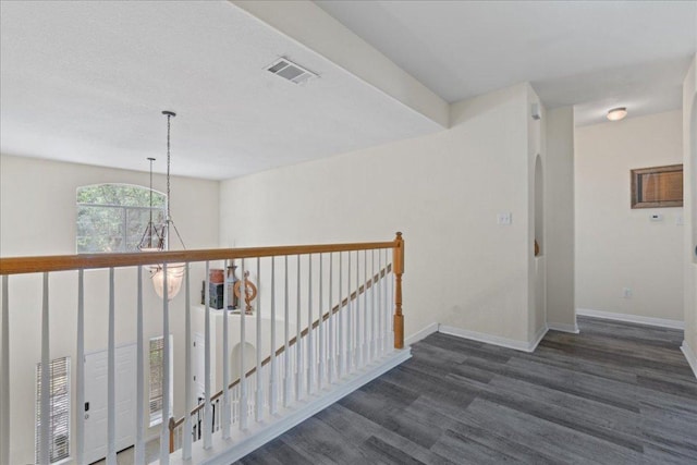 corridor featuring dark wood-style flooring, baseboards, and visible vents
