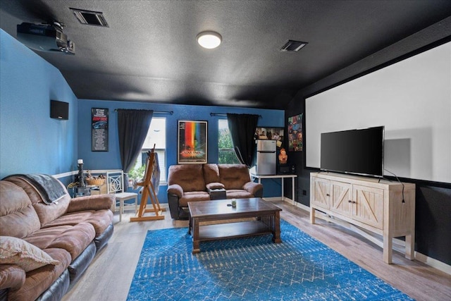interior space with a textured ceiling, visible vents, wood finished floors, and vaulted ceiling