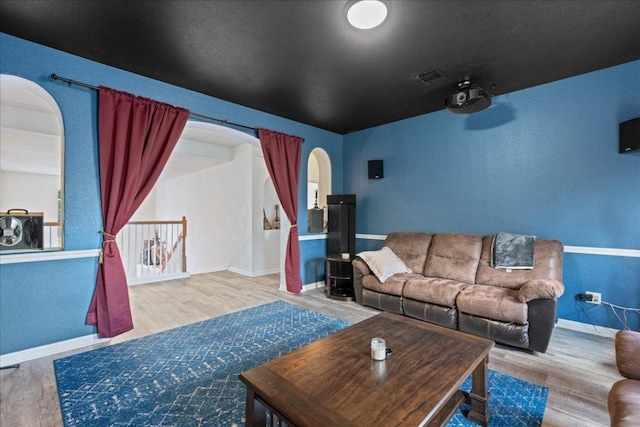 home theater room with arched walkways, baseboards, and wood finished floors
