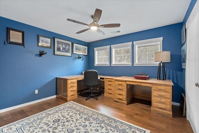 home office with a wealth of natural light, a ceiling fan, dark wood-style floors, and visible vents