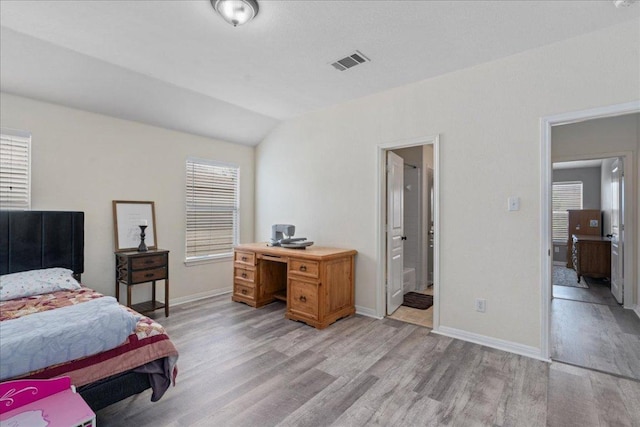 bedroom featuring baseboards, vaulted ceiling, light wood finished floors, and visible vents