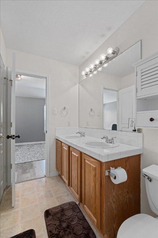 bathroom featuring double vanity, a sink, and toilet