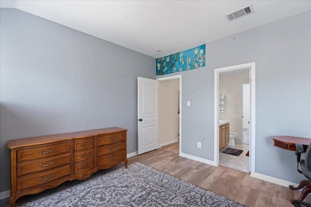 bedroom featuring baseboards, ensuite bathroom, wood finished floors, and visible vents