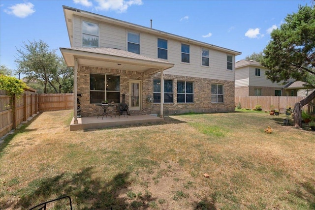 rear view of house featuring a fenced backyard, a patio, a lawn, and brick siding