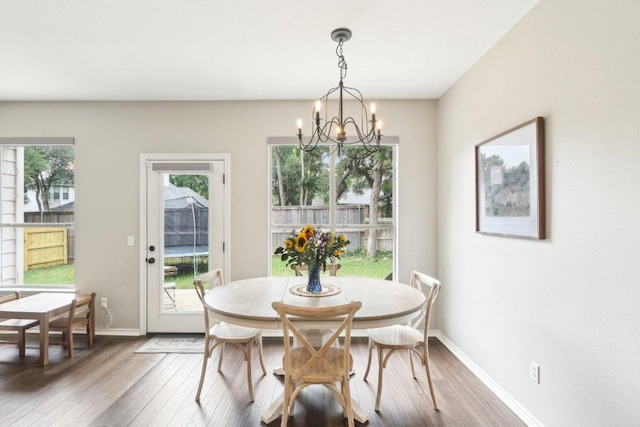 dining area with baseboards, an inviting chandelier, and wood finished floors