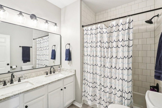 full bathroom featuring double vanity, a sink, shower / tub combo with curtain, and toilet