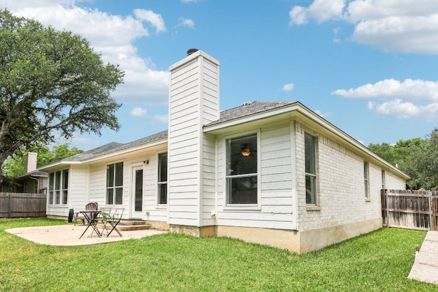 rear view of house featuring fence, a patio, a chimney, and a lawn