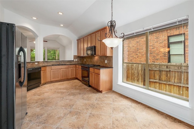 kitchen with dark countertops, tasteful backsplash, vaulted ceiling, a sink, and black appliances
