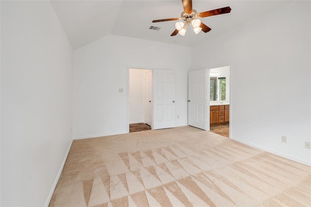 unfurnished bedroom featuring visible vents, light colored carpet, vaulted ceiling, baseboards, and connected bathroom
