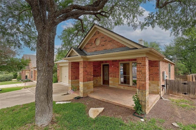 view of front facade featuring a porch, an attached garage, fence, and brick siding