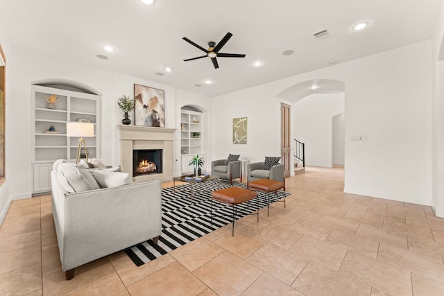 15 Borello Dr, Austin, TX 78738 - living room featuring built in features, a warm lit fireplace, a ceiling fan, recessed lighting, and arched walkways