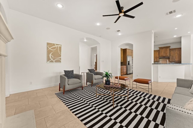 living room with a ceiling fan, visible vents, arched walkways, light tile patterned floors, and recessed lighting