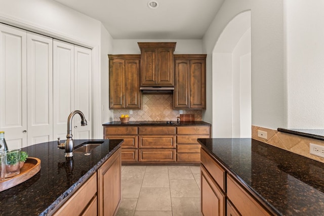 kitchen with under cabinet range hood, black electric cooktop, a sink, and tasteful backsplash