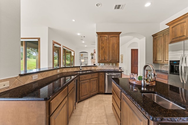 15 Borello Dr, Austin, TX 78738 - kitchen featuring stainless steel appliances, arched walkways, backsplash, recessed lighting, and dark stone counters