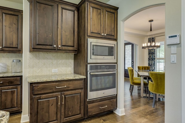 4101 Front Range Ln, Austin, TX 78732 - kitchen featuring appliances with stainless steel finishes, a chandelier, wood finished floors, arched walkways, and backsplash