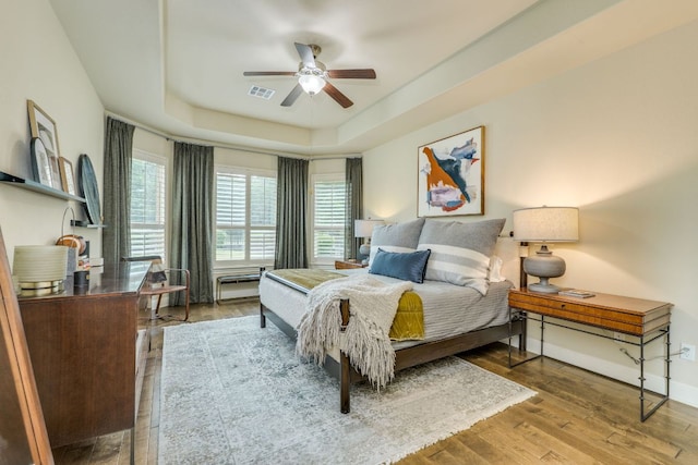 4101 Front Range Ln, Austin, TX 78732 - bedroom with visible vents, wood finished floors, baseboards, a tray ceiling, and a ceiling fan