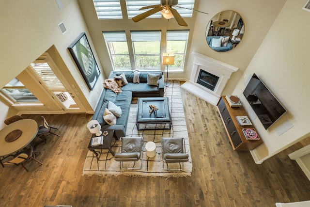 4101 Front Range Ln, Austin, TX 78732 - living room with wood-type flooring, visible vents, a glass covered fireplace, a high ceiling, and a ceiling fan