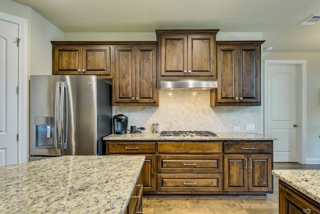 4101 Front Range Ln, Austin, TX 78732 - kitchen with stainless steel appliances, under cabinet range hood, light stone counters, backsplash, and light wood-style floors
