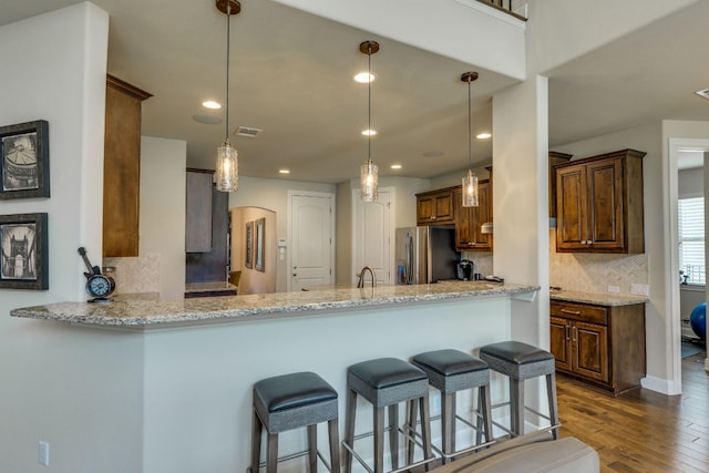 4101 Front Range Ln, Austin, TX 78732 - kitchen with dark wood-style flooring, arched walkways, tasteful backsplash, light stone counters, and stainless steel fridge