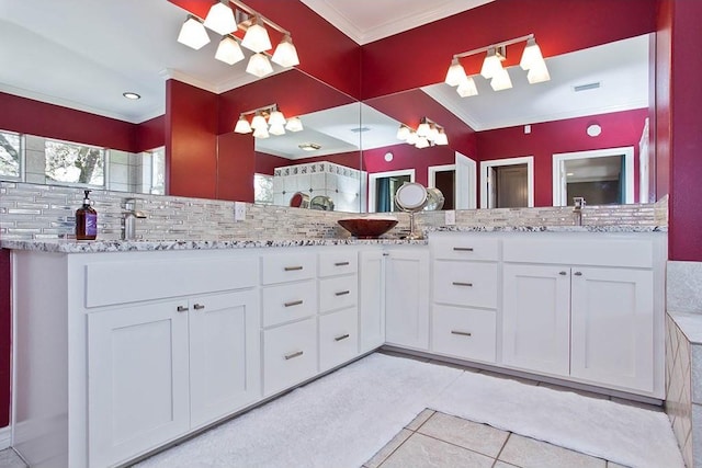 bathroom with crown molding, decorative backsplash, tile patterned flooring, double vanity, and a sink
