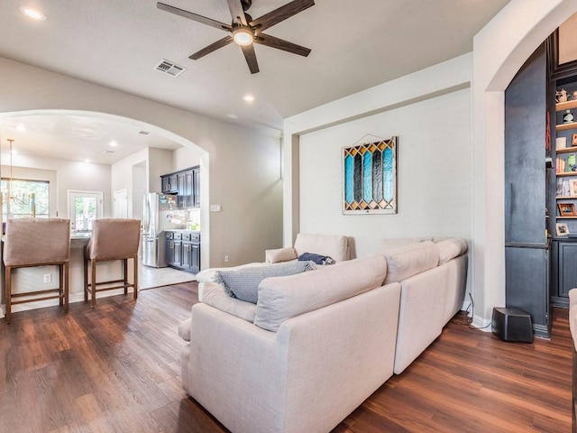 living area featuring dark wood-style flooring, ceiling fan, arched walkways, recessed lighting, and visible vents