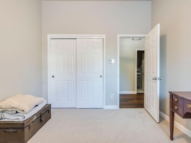 carpeted bedroom featuring baseboards and a closet