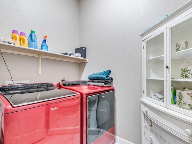 laundry area featuring a textured wall, laundry area, washing machine and dryer, and baseboards