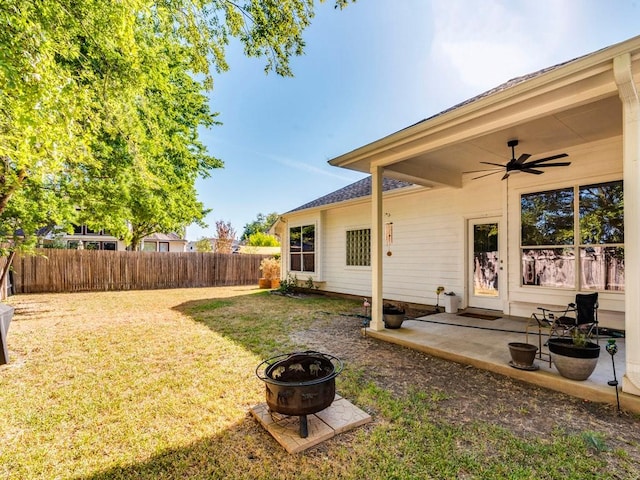view of yard featuring a fire pit, a ceiling fan, a fenced backyard, and a patio area