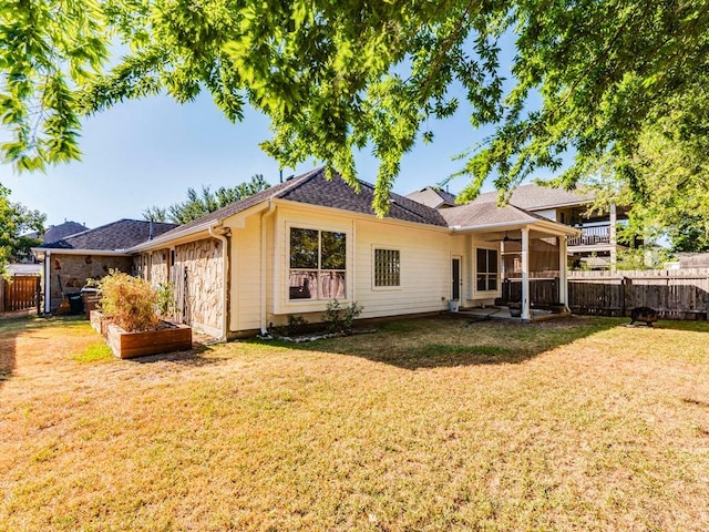 rear view of property with a fenced backyard, ceiling fan, and a yard