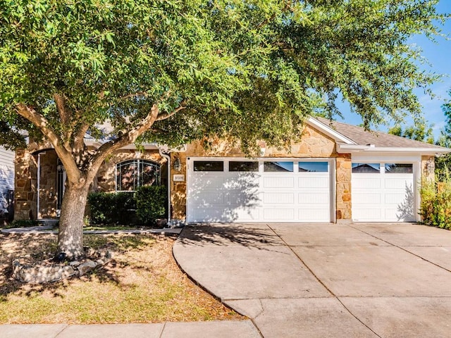 obstructed view of property with a garage, concrete driveway, and stone siding