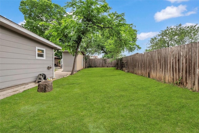 view of yard with a storage unit, a fenced backyard, and an outbuilding