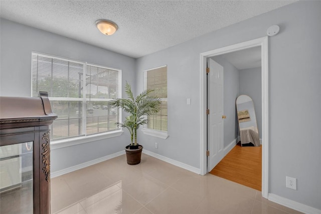 interior space with a textured ceiling, baseboards, and tile patterned floors