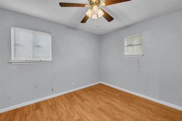 unfurnished room with a textured ceiling, baseboards, and light wood finished floors