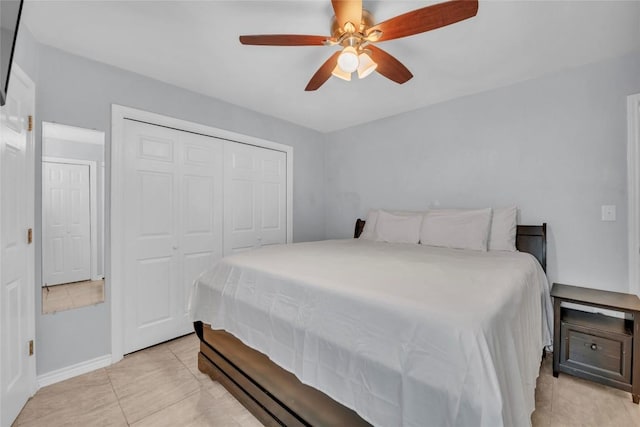 bedroom featuring a ceiling fan, baseboards, light tile patterned flooring, and a closet
