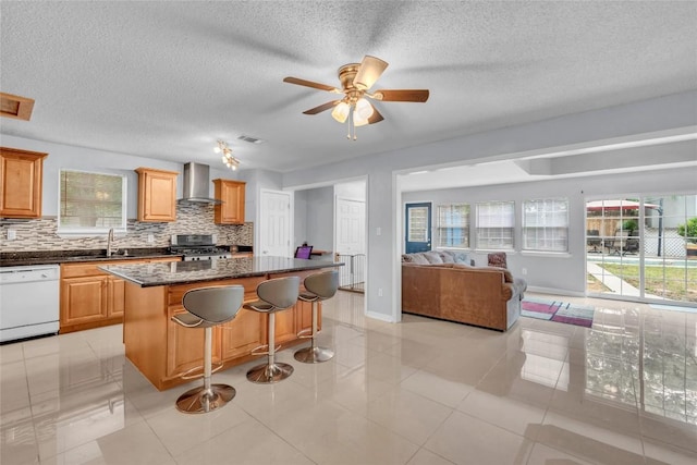 kitchen featuring white dishwasher, decorative backsplash, open floor plan, and wall chimney range hood