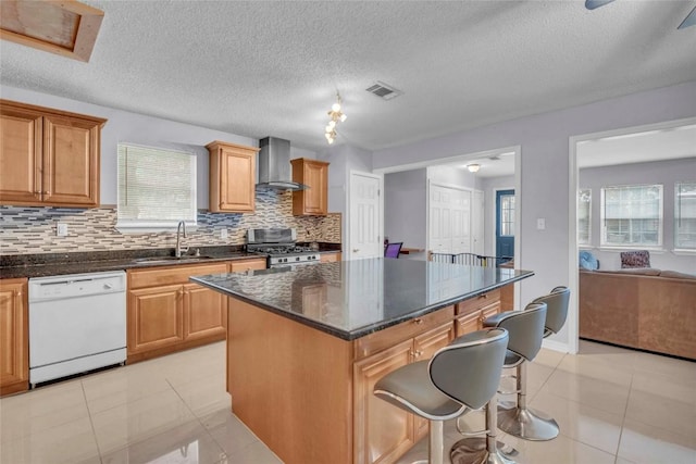 kitchen with a sink, dishwasher, stainless steel range with gas stovetop, plenty of natural light, and wall chimney exhaust hood