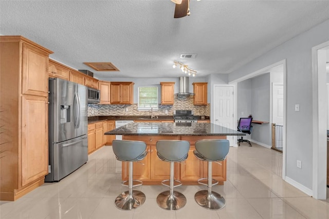 kitchen with wall chimney range hood, visible vents, tasteful backsplash, a sink, and stainless steel appliances