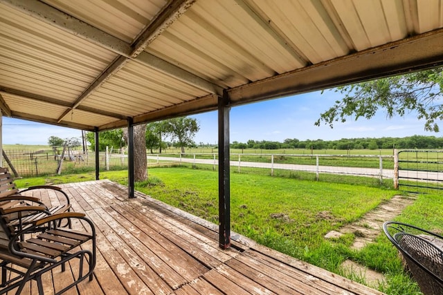 wooden terrace featuring fence, a lawn, and a rural view