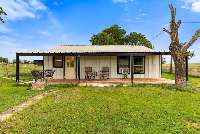 back of property featuring a lawn, cooling unit, and metal roof