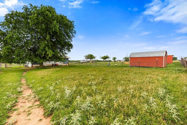 view of yard featuring fence, an outbuilding, and a rural view