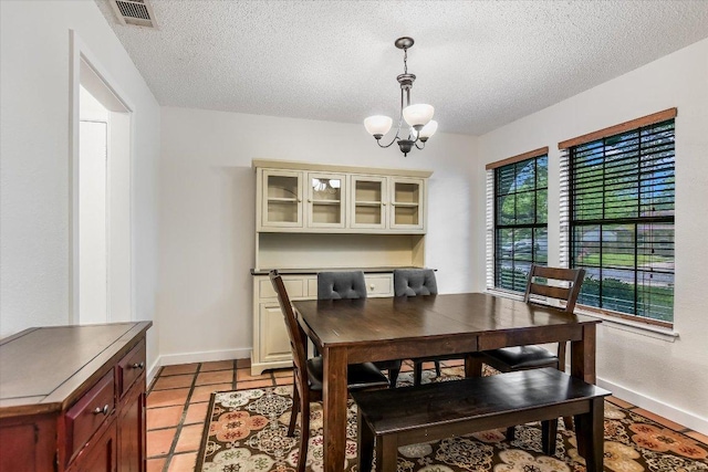 2604 Fentonridge Dr, Austin, TX 78745 - dining area with a chandelier, a textured ceiling, baseboards, and light tile patterned flooring