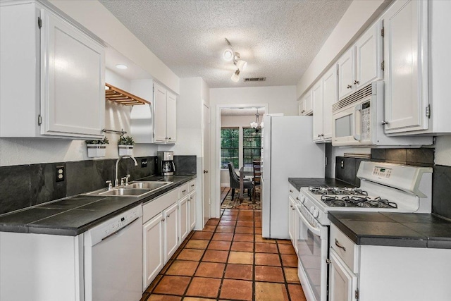 2604 Fentonridge Dr, Austin, TX 78745 - kitchen with white appliances, a sink, dark countertops, white cabinets, and a textured ceiling