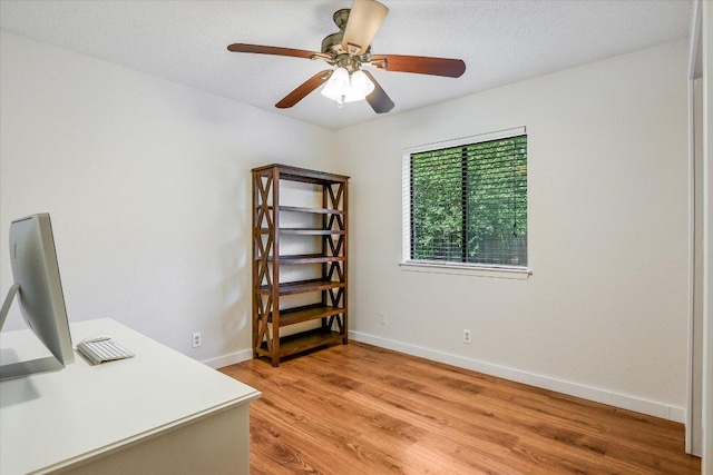 home office featuring light wood-style floors, a ceiling fan, and baseboards