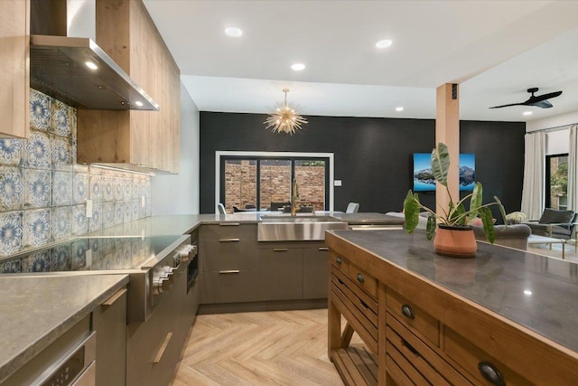 kitchen with stainless steel counters, recessed lighting, wall chimney exhaust hood, a sink, and backsplash