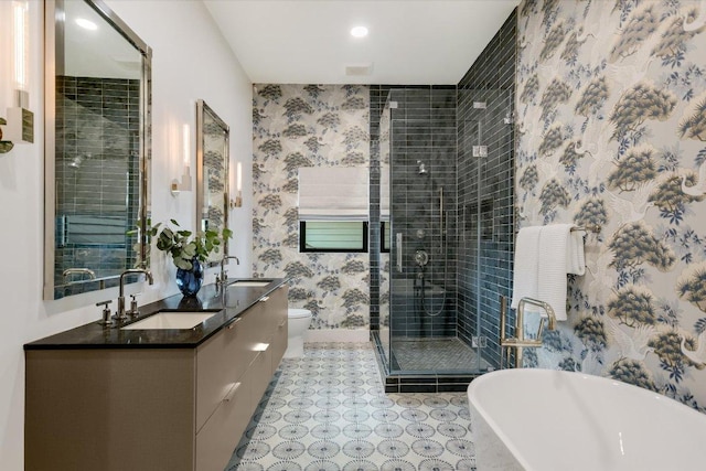 bathroom featuring a sink, double vanity, wallpapered walls, a freestanding tub, and a shower stall
