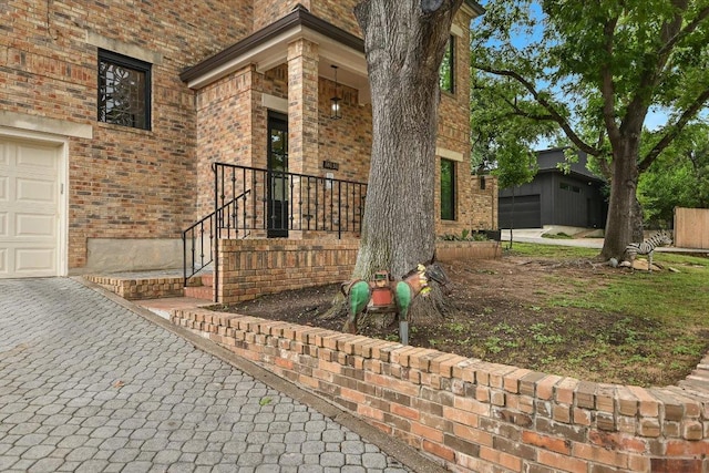 view of exterior entry with brick siding and a garage