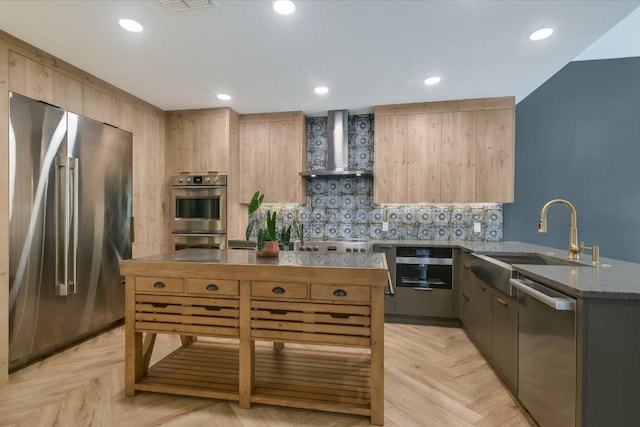 kitchen featuring a sink, decorative backsplash, wall chimney range hood, and stainless steel appliances