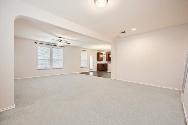 unfurnished living room featuring dark carpet, a ceiling fan, baseboards, and visible vents