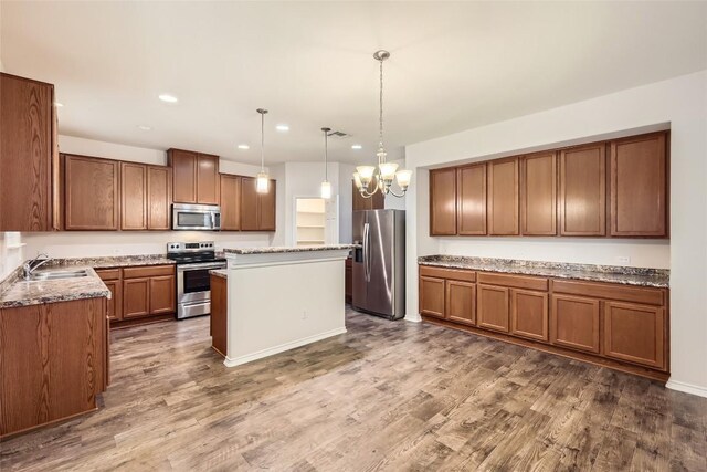 kitchen with a notable chandelier, appliances with stainless steel finishes, a sink, recessed lighting, and a kitchen island