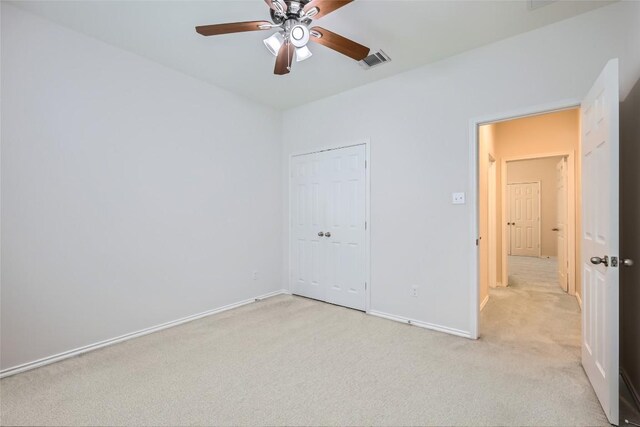 unfurnished bedroom with a ceiling fan, visible vents, baseboards, a closet, and light carpet